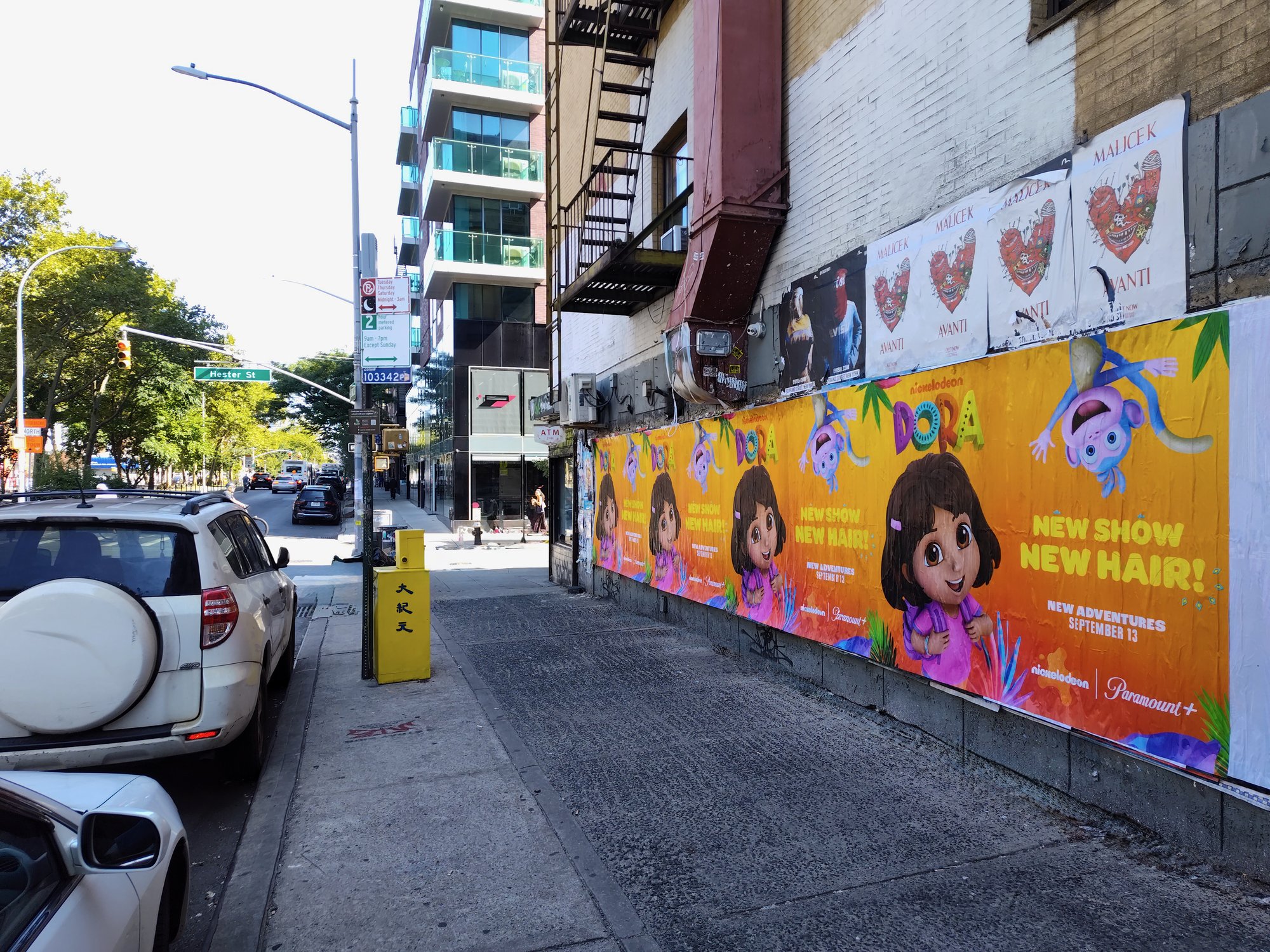 Nickelodeon Dora wild posting at Hester Street scale across construction wall, Lower East Side Manhattan